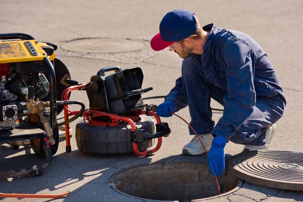 Plumber,Prepares,To,Fix,The,Problem,In,The,Sewer,With Plumber prepares to fix the problem in the sewer with portable camera for pipe inspection and other plumbing work.