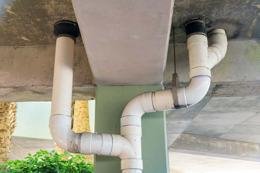 White,Pvc,Drain,Pipes,Below,The,Parking,Garage,Building,In White pvc drain pipes below the parking garage building in Destin, Florida. Views of drainage pipe near the concrete painted pillar from below.