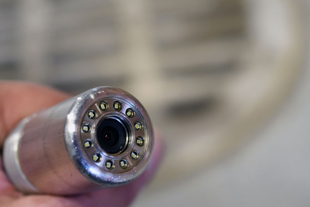 client talking to plumber holding pipe camera